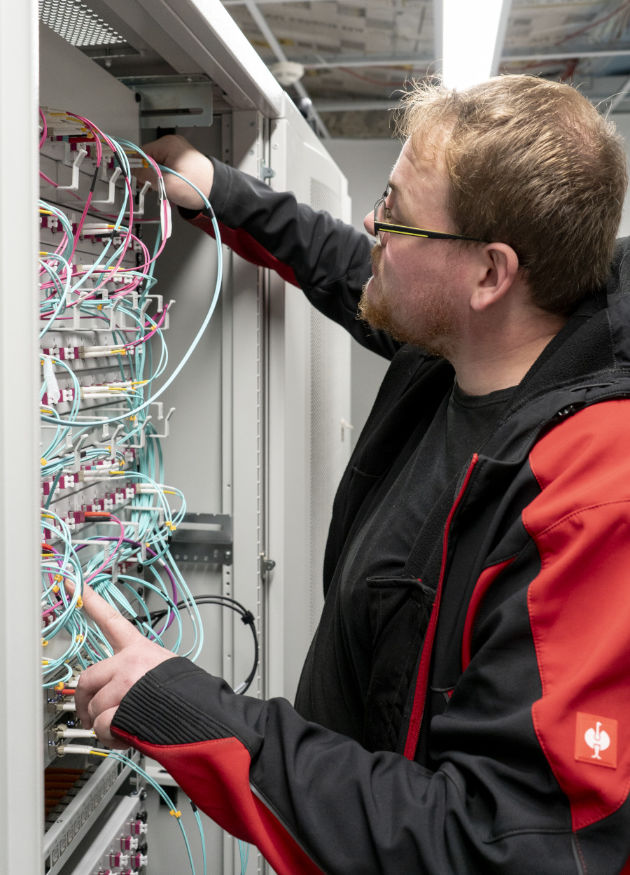 Techniker arbeitet an einem Server-Schrank mit farbigen Kabeln in einem modernen Rechenzentrum. Techniker arbeitet an einem Server-Schrank mit farbigen Kabeln in einem modernen Rechenzentrum.