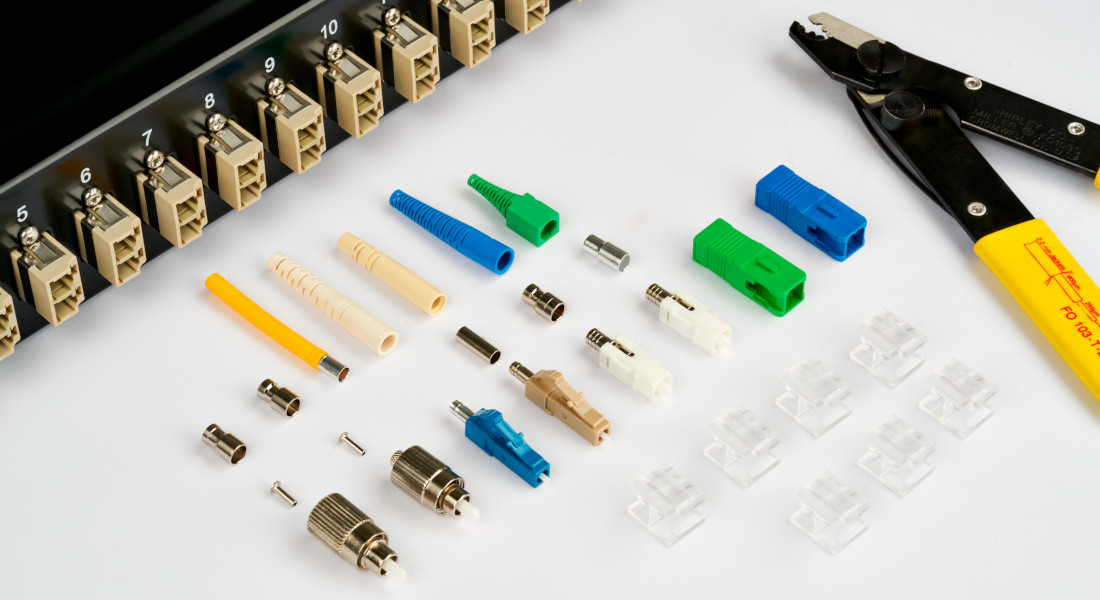 Various fiber optic couplers in front of a patch panel with numbered ports. Various fiber optic couplers in front of a patch panel with numbered ports.