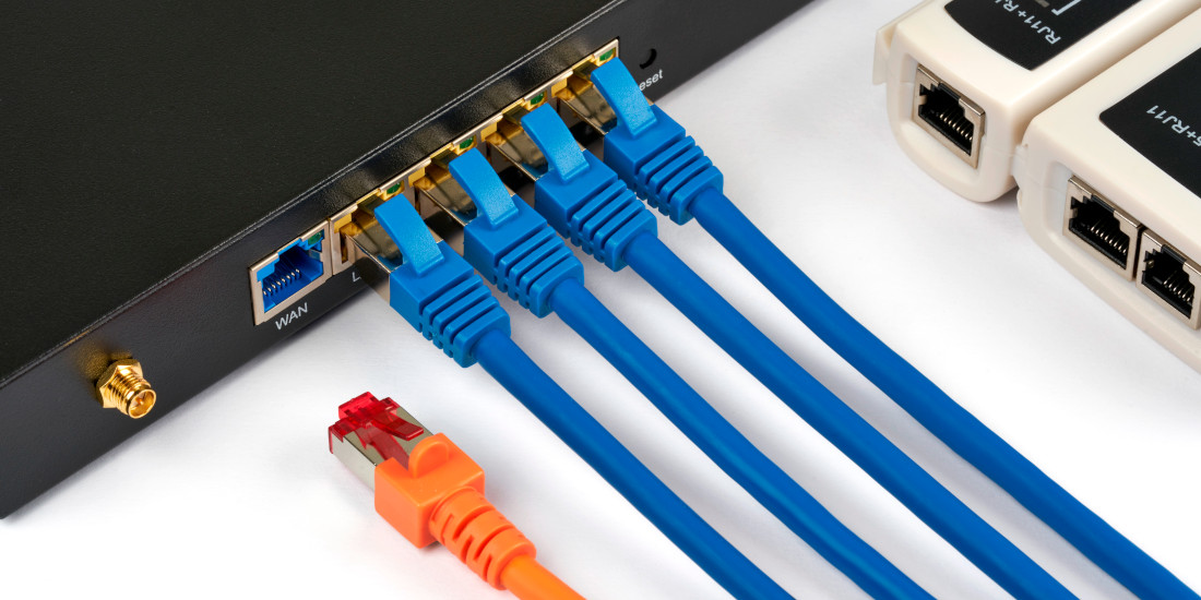 Netzwerk-Hardware mit blauen Ethernet-Kabeln und orangefarbenem Stecker für Datenverbindungen. Netzwerk-Hardware mit blauen Ethernet-Kabeln und orangefarbenem Stecker für Datenverbindungen.