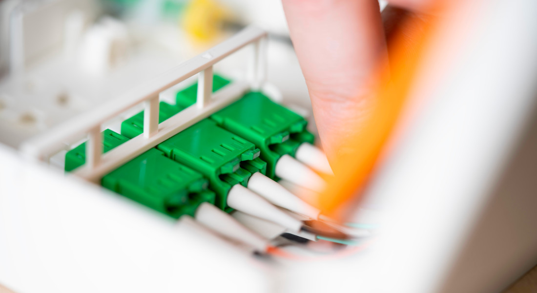 Close-up of green fiber optic connectors in a white holder, hand touching one of the connectors. Close-up of green fiber optic connectors in a white holder, hand touching one of the connectors.