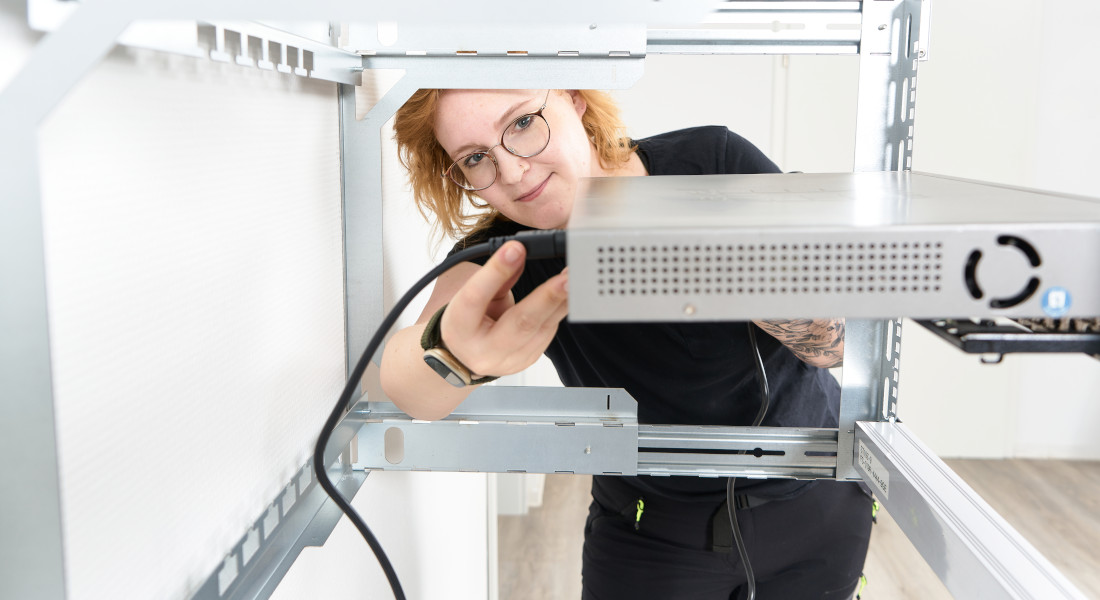 Frau befestigt Kabel an Komponenten im X-Rack Frau befestigt Kabel an Komponenten im X-Rack
