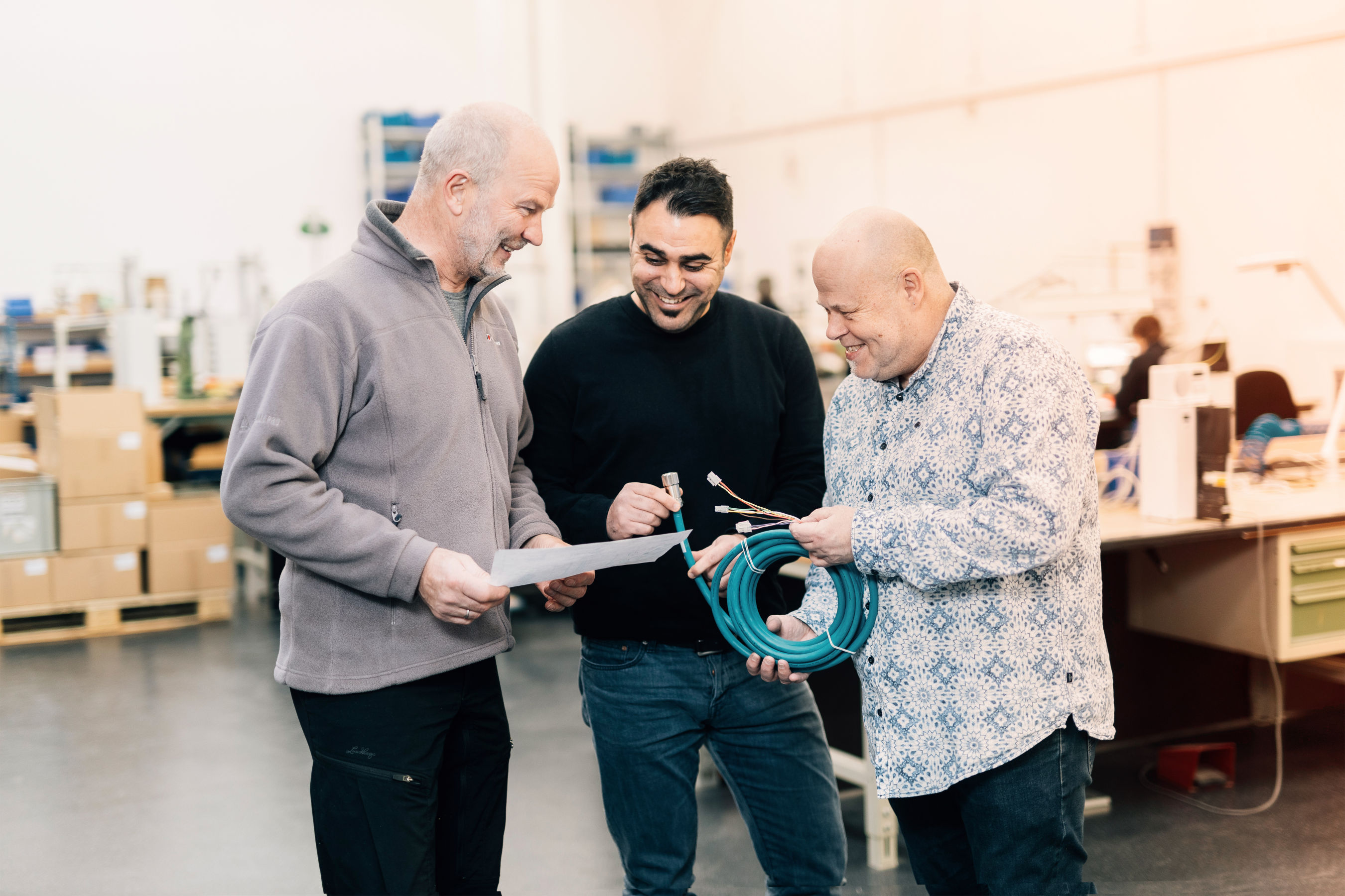 Three men inspect cable, EFB-Elektronik