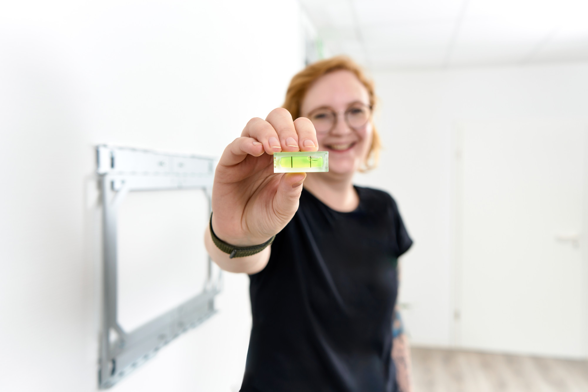 Frau zeigt die im X-Rack Paket enthaltene Wasserwaage Frau zeigt die im X-Rack Paket enthaltene Wasserwaage