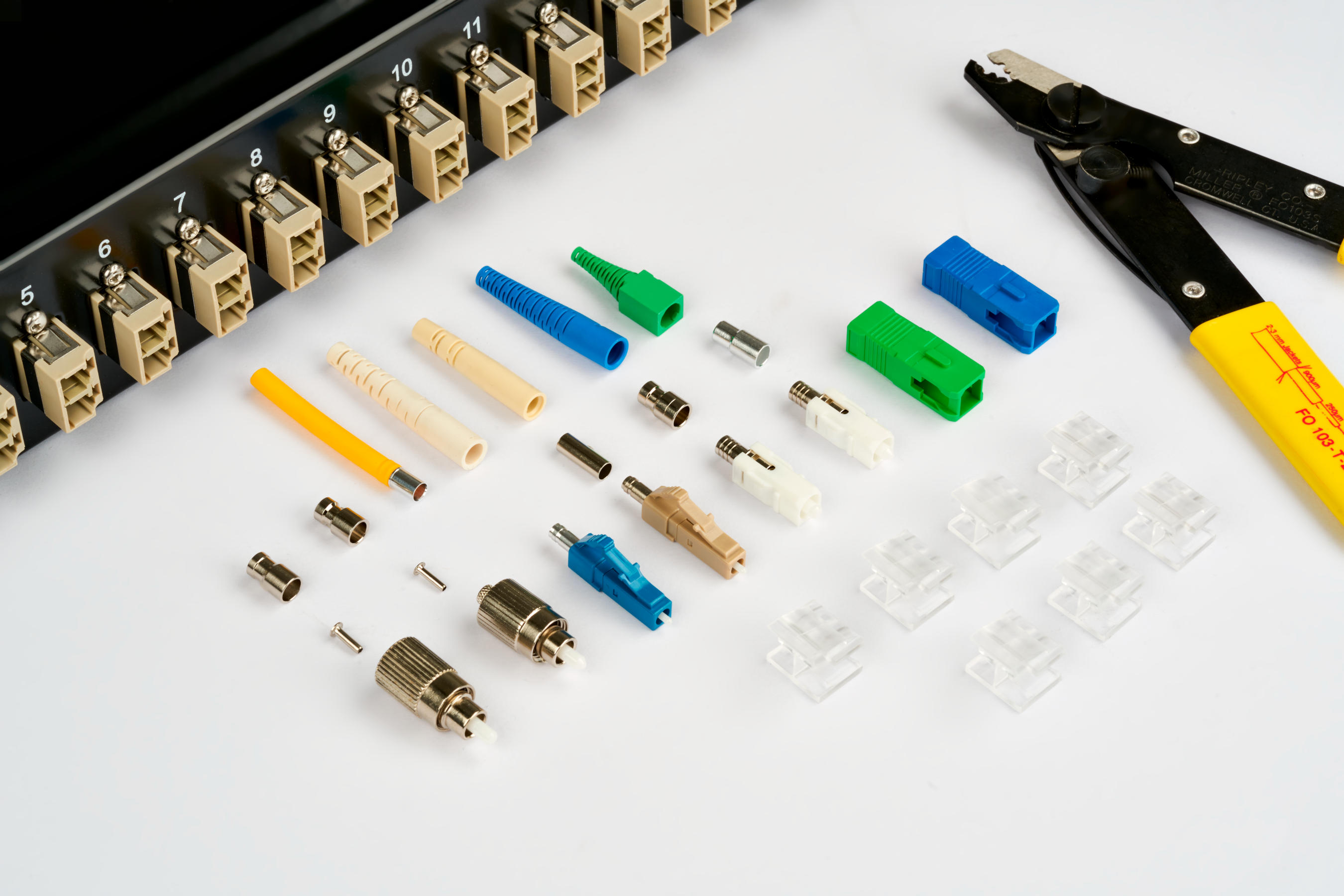 Various fiber optic couplers in front of a patch panel with numbered ports.