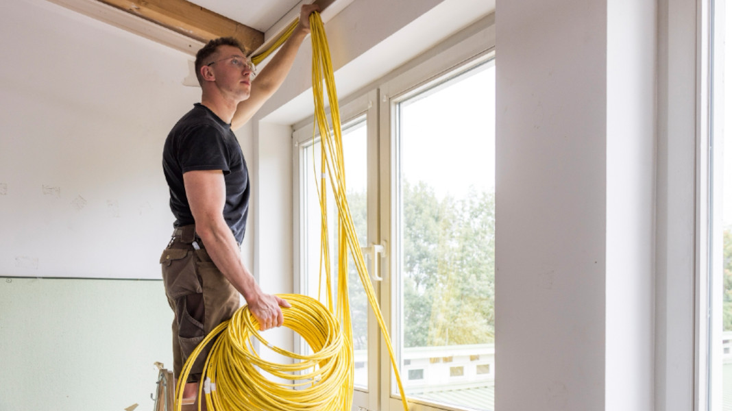 Handwerker verlegt gelbe Netzwerkkabel an der Decke – professionelle Installation strukturierter IT-Verkabelung Handwerker verlegt gelbe Netzwerkkabel an der Decke – professionelle Installation strukturierter IT-Verkabelung