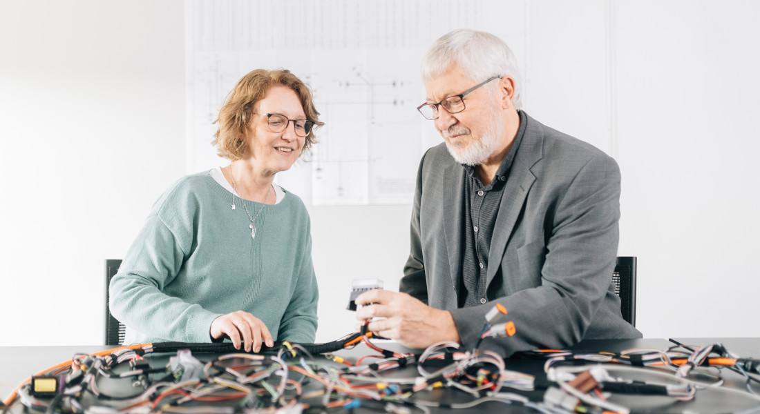 Mann und Frau inspizieren Kabel, EFB-Elektronik