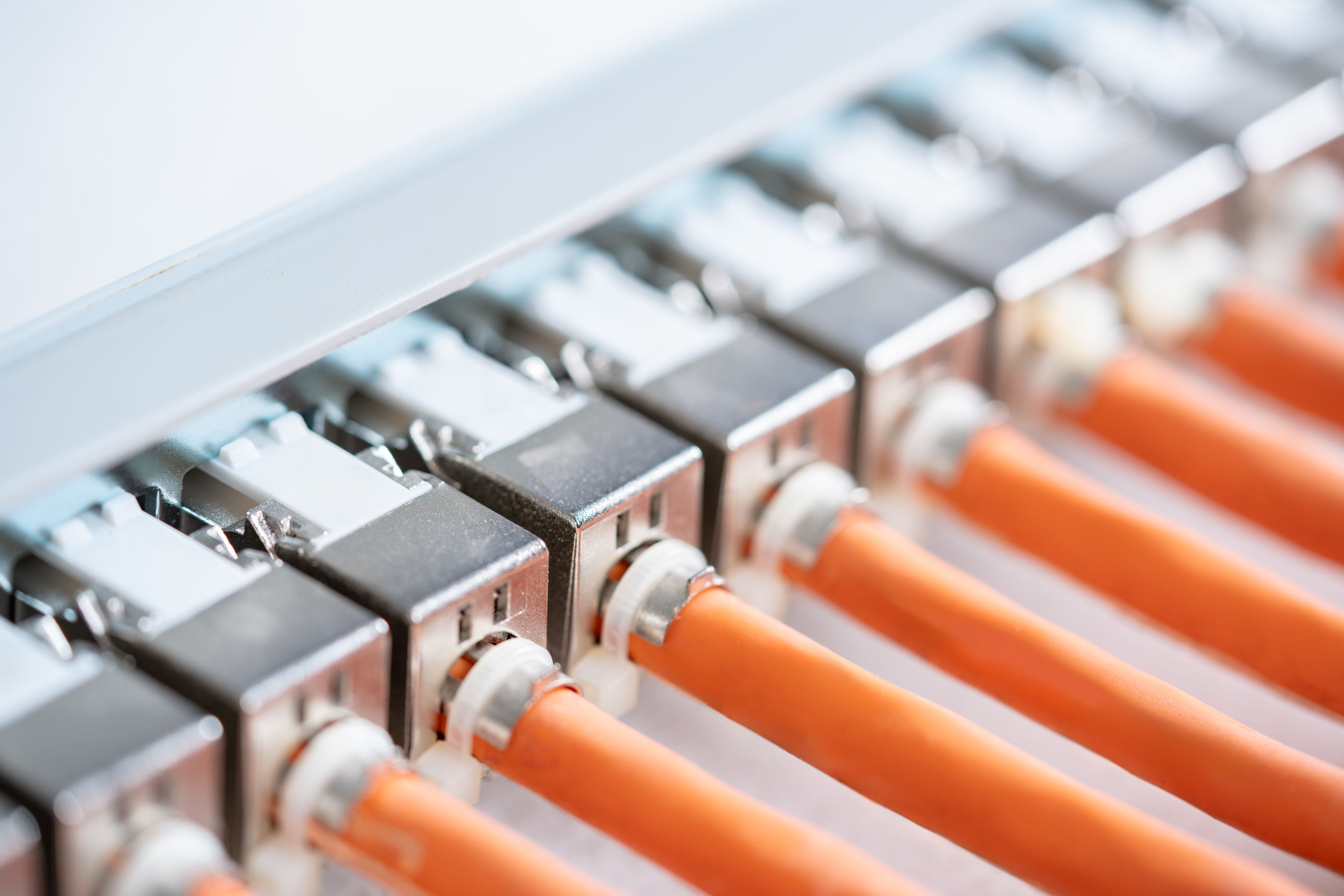 Hochwertige Netzwerkverkabelung mit angeschlossenen, orangefarbenen Netzwerkkabeln in einer strukturierten IT-Infrastruktur.
