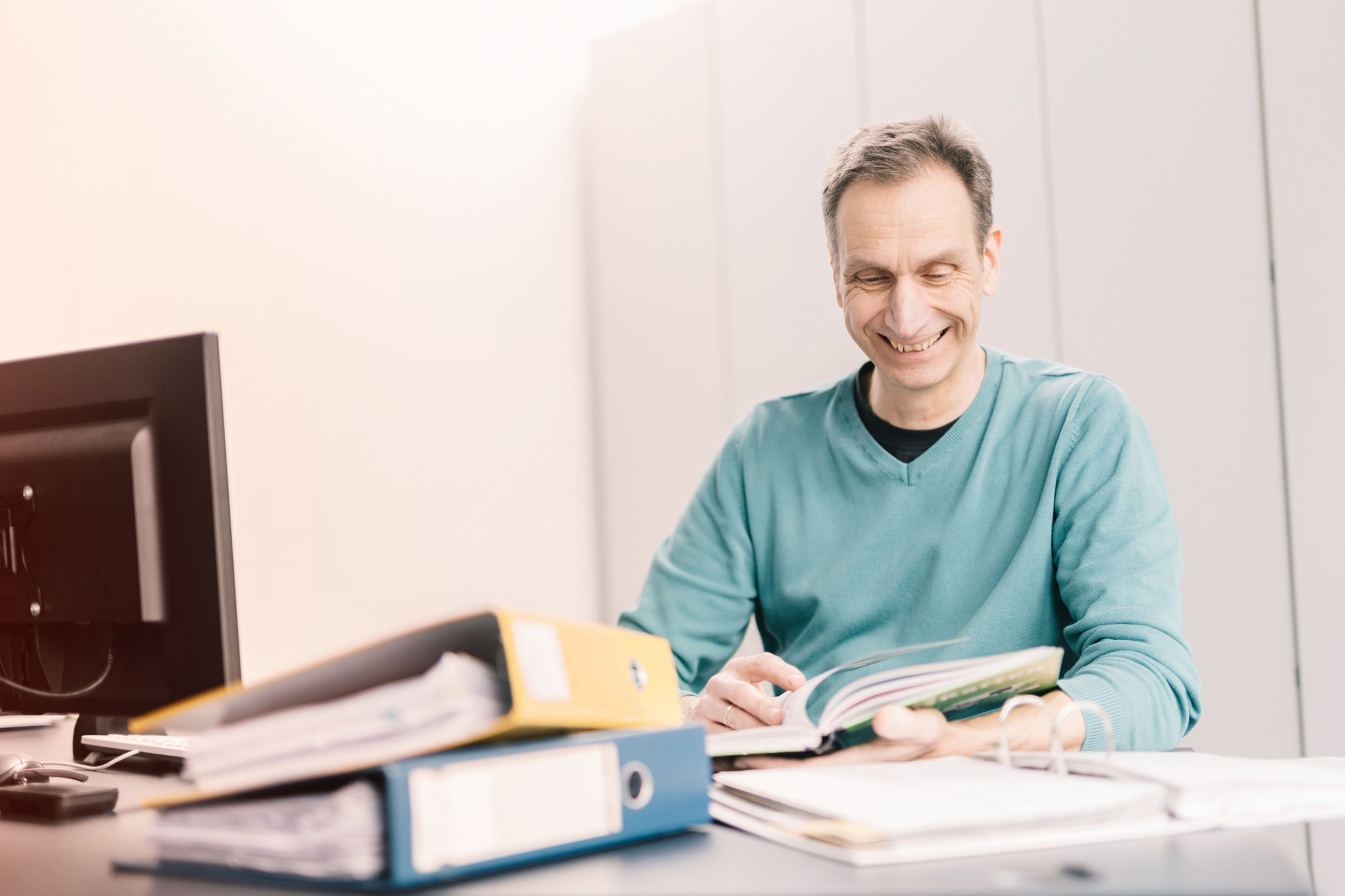 EFB-Elektronik employee in the office at a table. Folders are lying on the table. The employee looks something up and rummages through the documents.