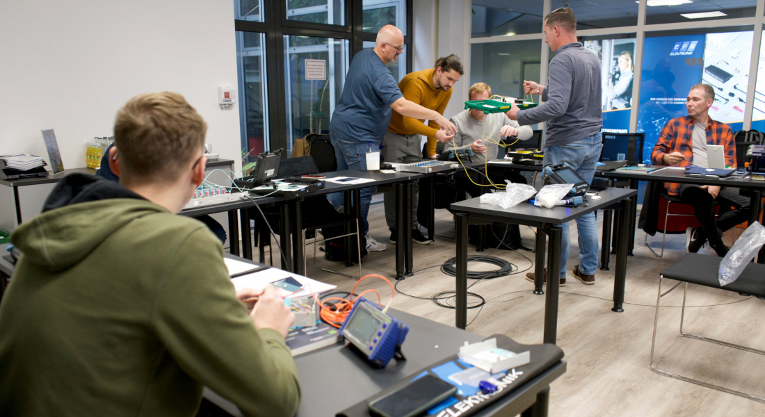 Workshopteilnehmer an Tischen im praktischen Umgang mit Geräten