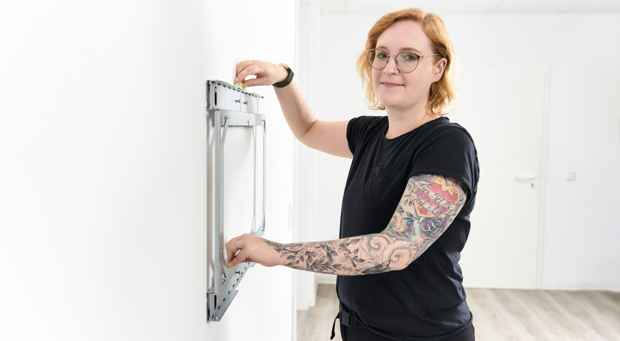 Frau kontrolliert Aufhängung des X-Racks mit der beigelegten Wasserwaage Frau kontrolliert Aufhängung des X-Racks mit der beigelegten Wasserwaage
