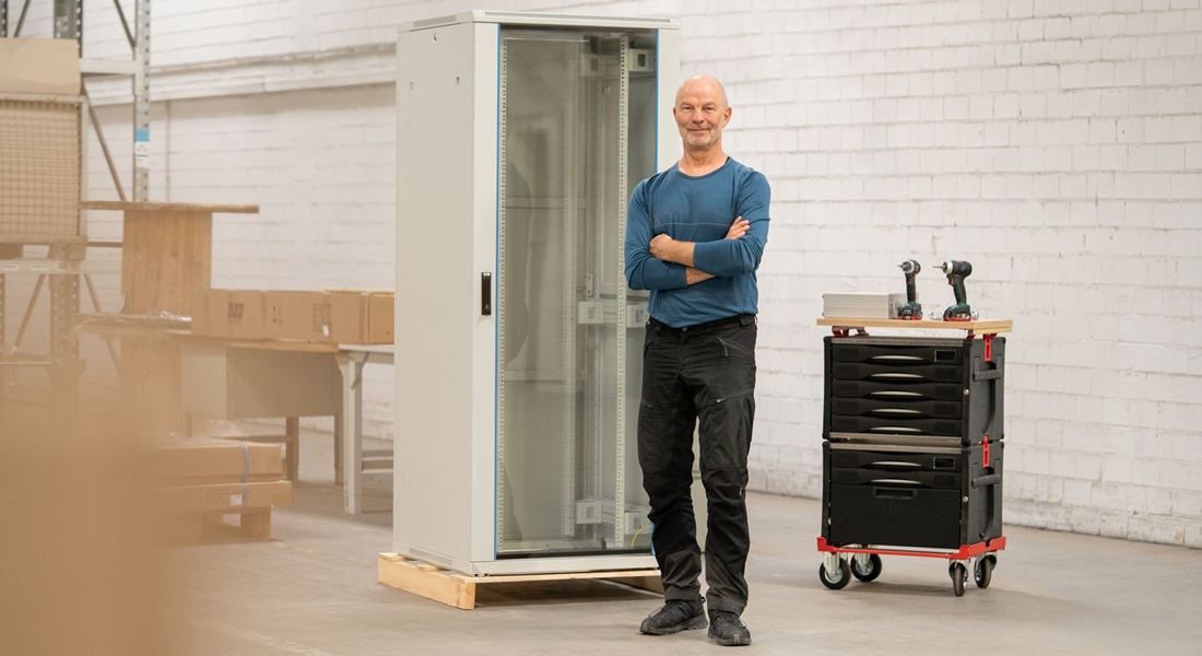 Ein Mann steht in einer Halle vor einem 19" Netzwerkschrank