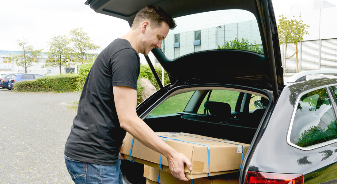 Mann nimmt X-Rack Verpackung aus dem Kofferraum eines Autos Mann nimmt X-Rack Verpackung aus dem Kofferraum eines Autos