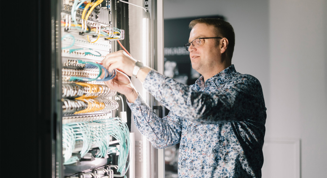 Product manager leans against a server cabinet in a relaxed and friendly manner, talking to colleagues | EFB-Elektronik