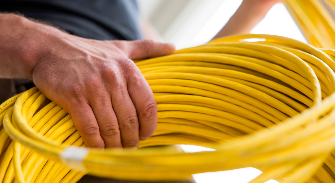Nahaufnahme einer Hand mit gelber Kabeltrommel – professionelle Netzwerkverkabelung für IT-Infrastrukturen Nahaufnahme einer Hand mit gelber Kabeltrommel – professionelle Netzwerkverkabelung für IT-Infrastrukturen