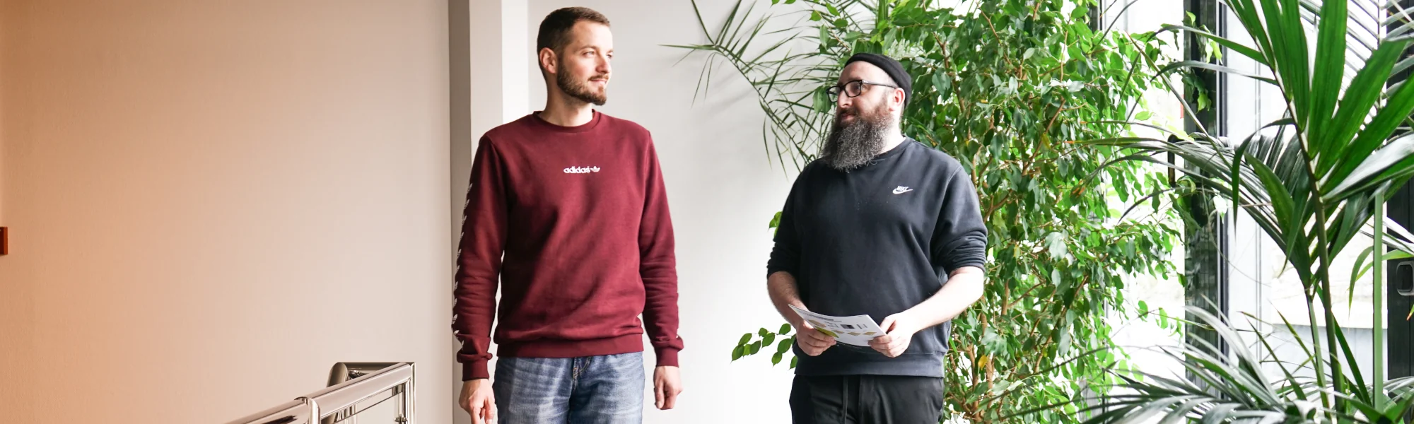 Zwei Mitarbeiter von EFB-Elektronik im Gespräch in einem hellen Bürogebäude mit vielen Grünpflanzen