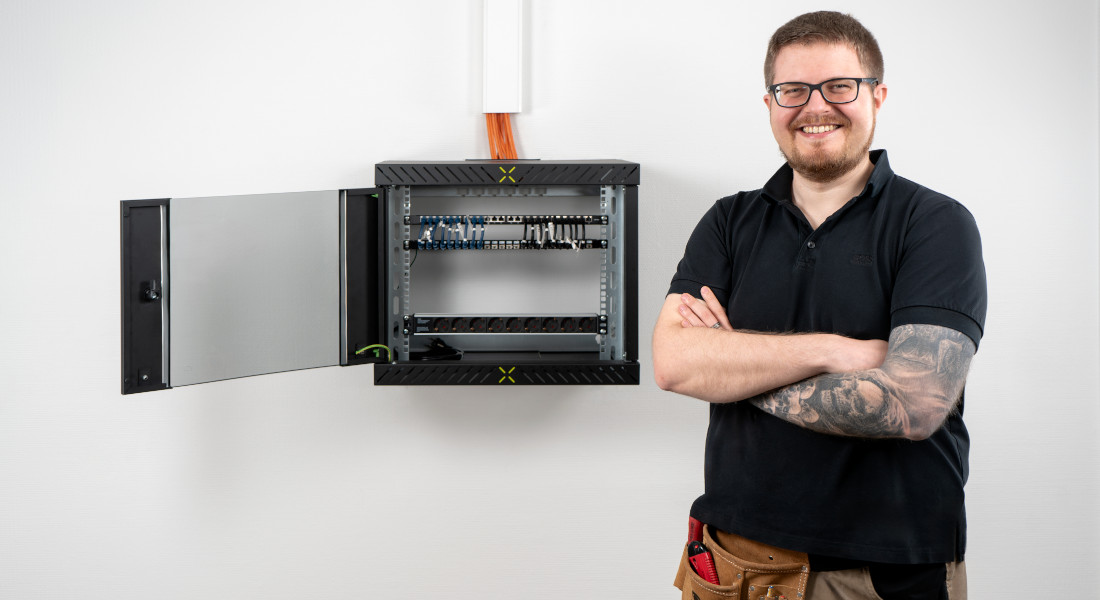 Mann posiert vor fertig montiertem X-Rack mit aufgeklappter Tür