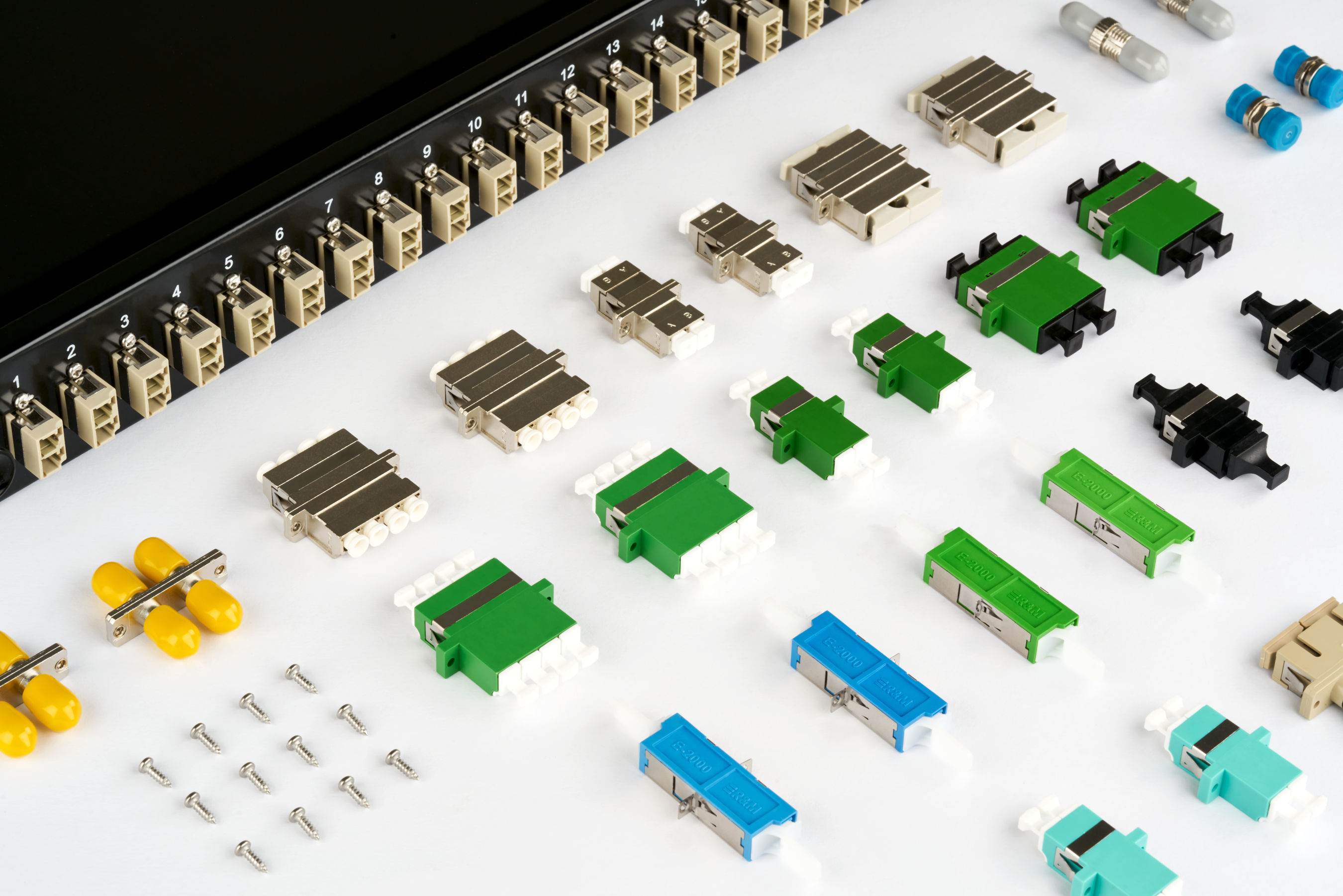 Verschiedene Glasfaser-Kupplungen vor einem Patchpanel mit nummerierten Ports.