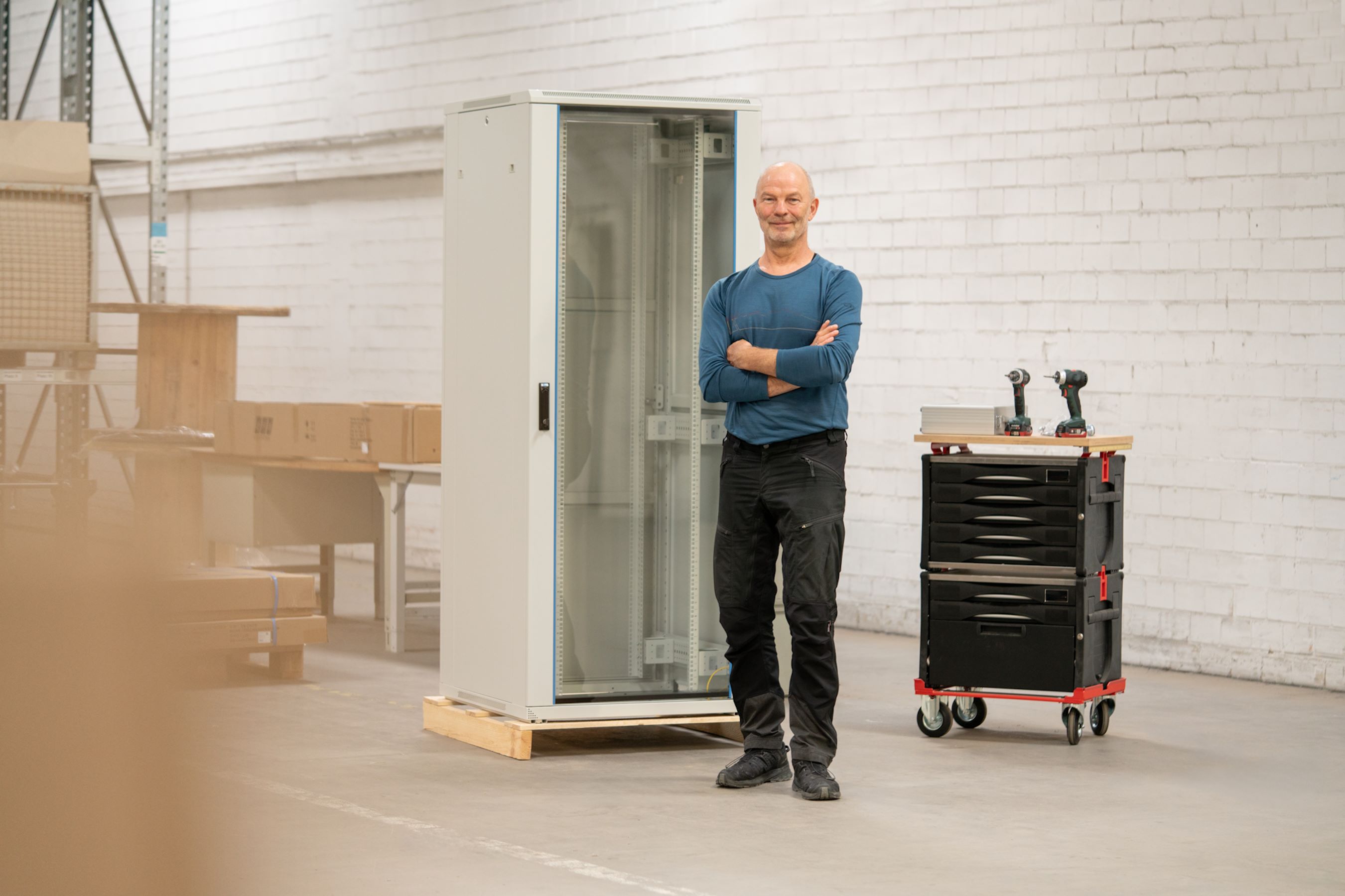 Ein Mann steht in einer Halle vor einem 19" Netzwerkschrank
