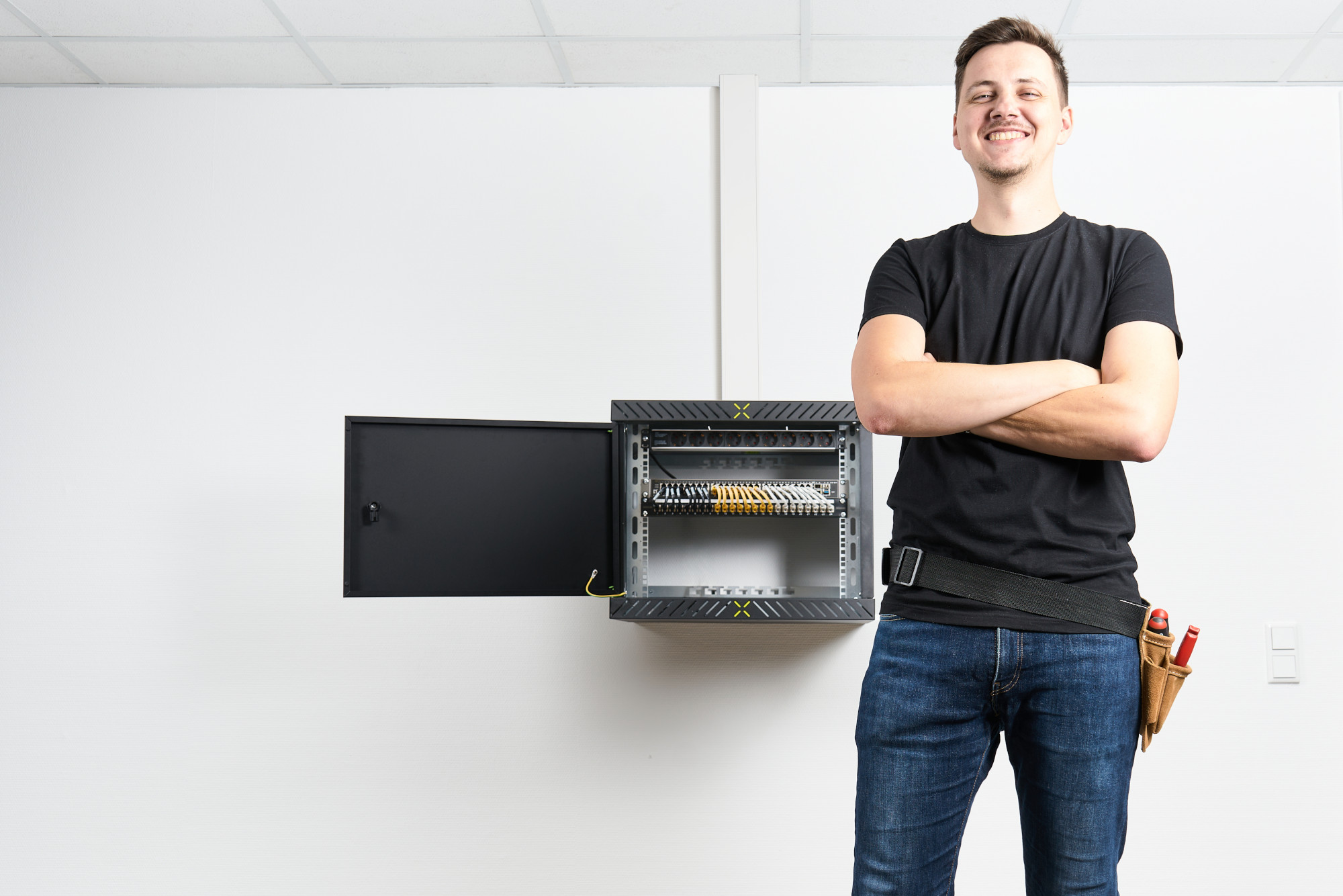 Mann posiert vor fertig montiertem X-Rack mit aufgeklappter Tür Mann posiert vor fertig montiertem X-Rack mit aufgeklappter Tür