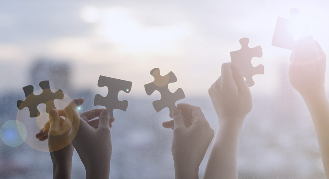 Five hands are holding up one puzzle piece each Five hands are holding up one puzzle piece each