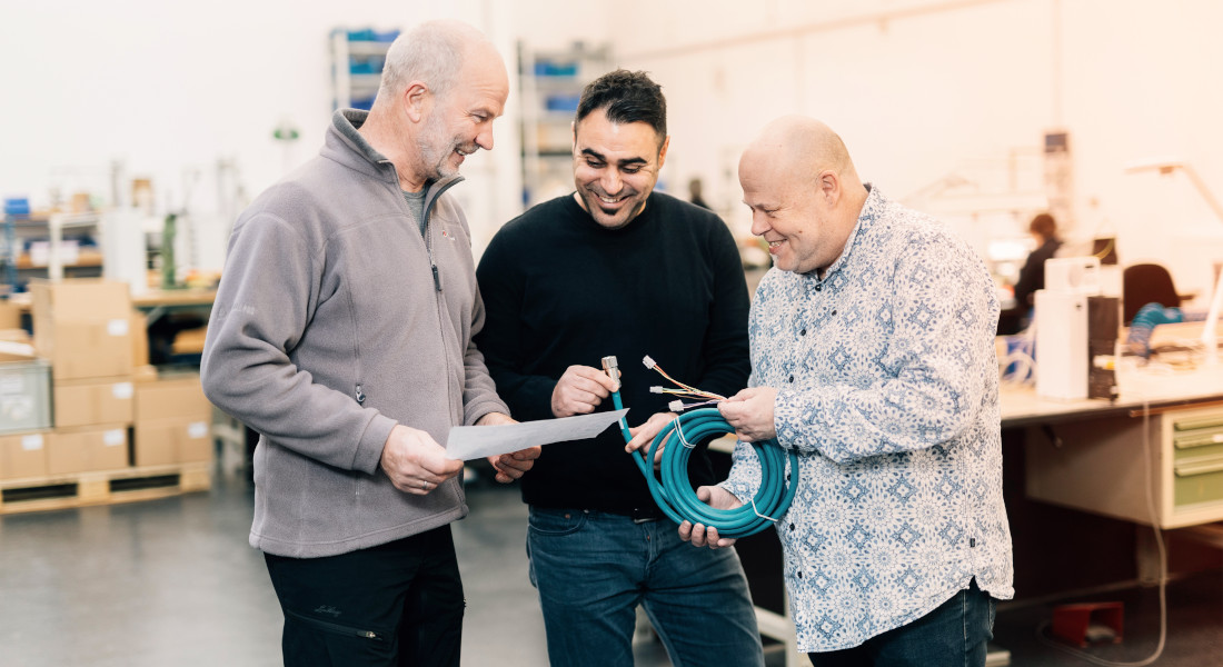 Three men inspect cable, EFB-Elektronik