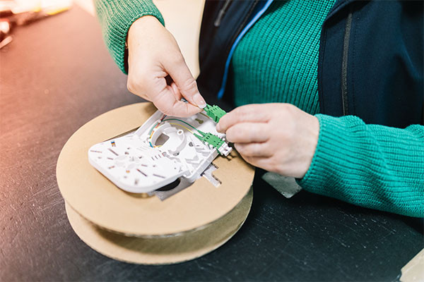 Person verbindet ein LWL-Kabel mit einer Spleißkassette. Person verbindet ein LWL-Kabel mit einer Spleißkassette.