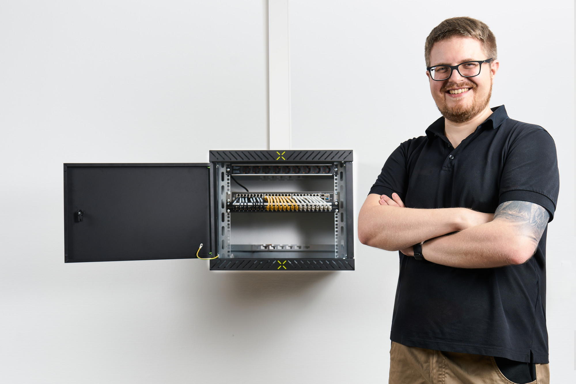 Mann posiert vor fertig montiertem X-Rack mit aufgeklappter Tür Mann posiert vor fertig montiertem X-Rack mit aufgeklappter Tür